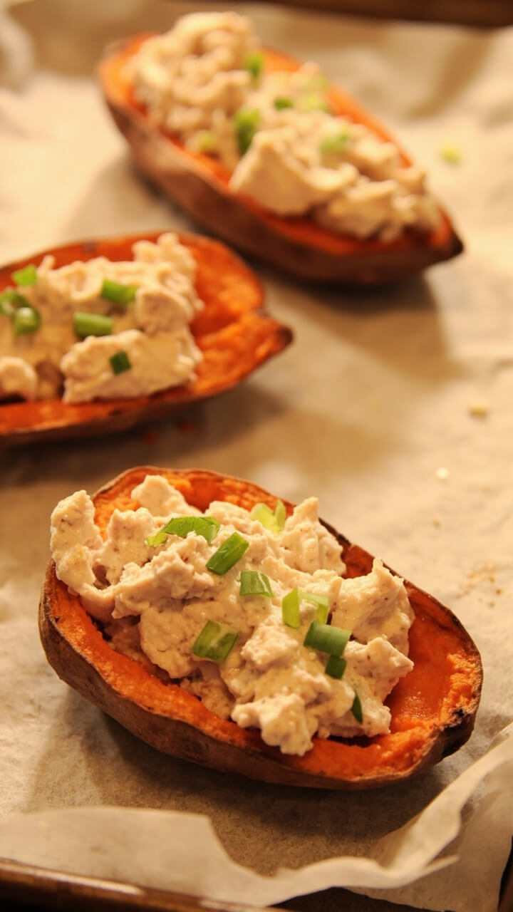 Baked sweet potato halves, hollowed and filled with a creamy tuna and Greek yogurt mix, sprinkled with green scallions. All arranged on a parchment-lined sheet pan, ready for scooping. Baked sweet potato halves, hollowed and filled with a creamy tuna and Greek yogurt mix, sprinkled with green scallions. All arranged on a parchment-lined sheet pan, ready for scooping.