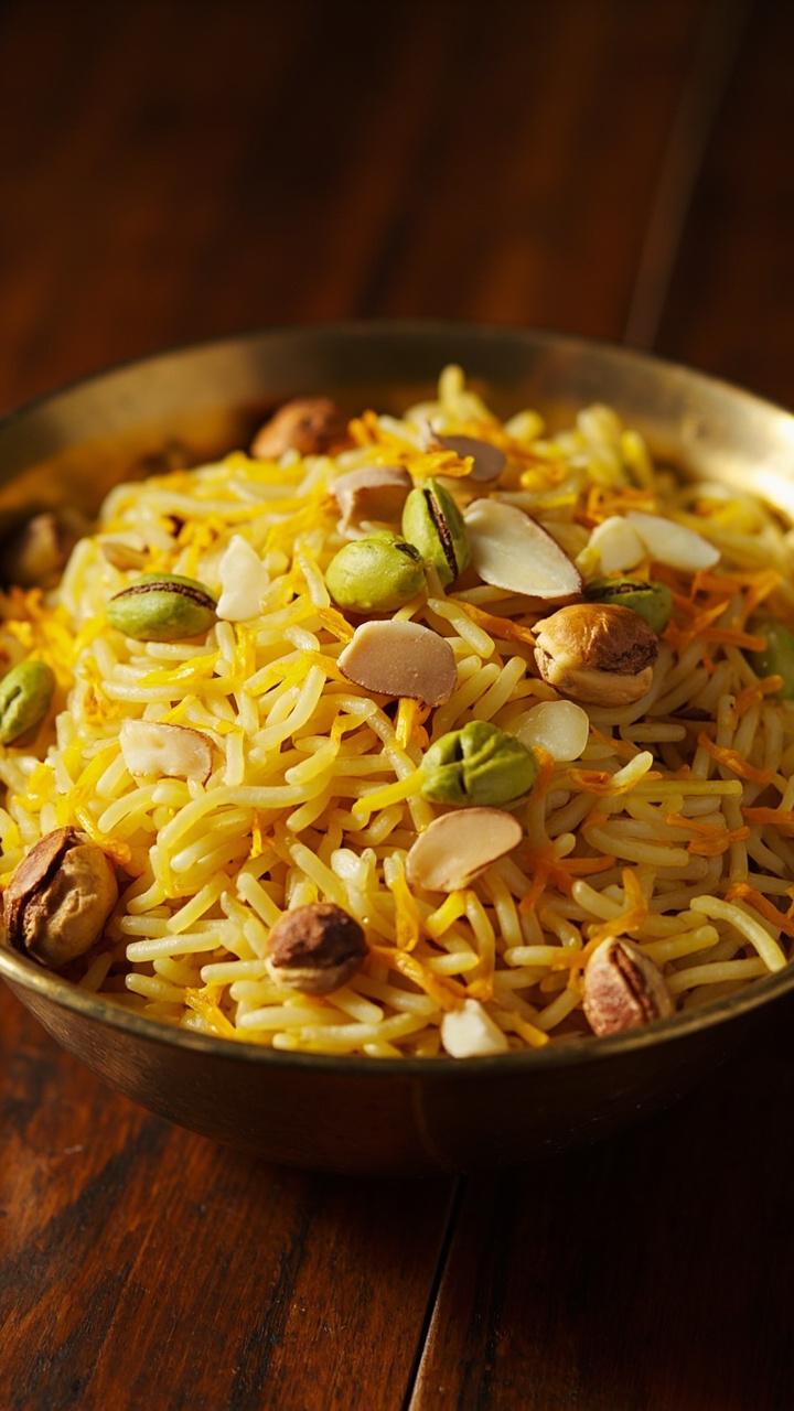 Golden tinted rice grains with faint saffron streaks, whole green cardamom pods visible, served in a shallow brass bowl, few slivered almonds and pistachios scattered on top, rich wood table surface. Golden tinted rice grains with faint saffron streaks, whole green cardamom pods visible, served in a shallow brass bowl, few slivered almonds and pistachios scattered on top, rich wood table surface.